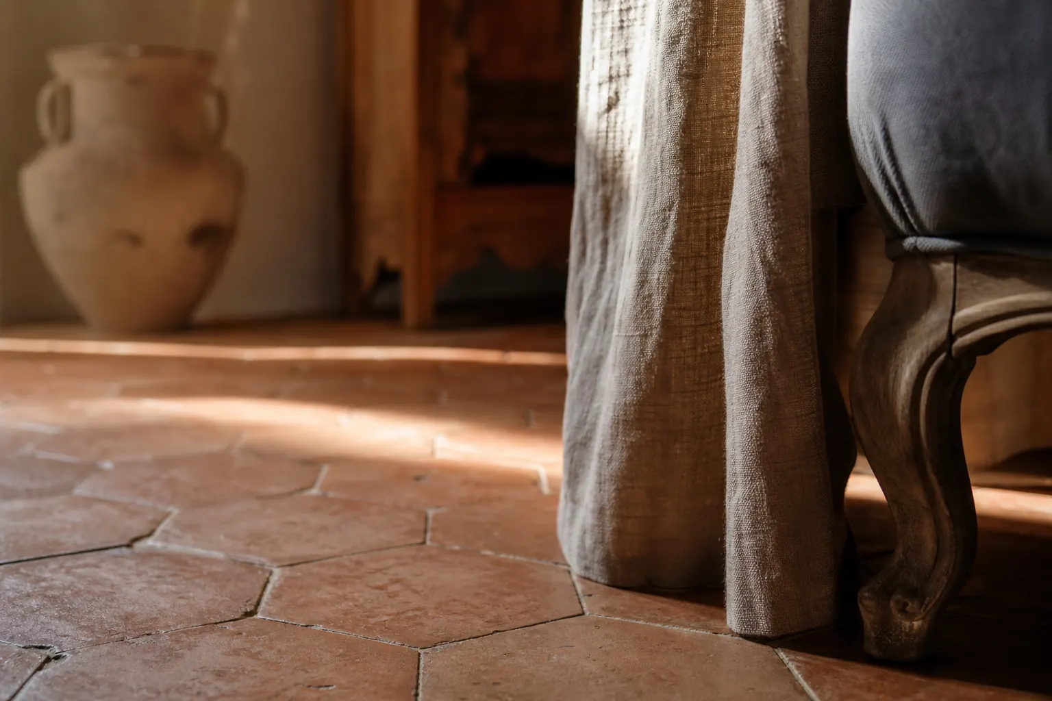 Sol de tomettes hexagonales en terre cuite et pied de fauteuil au premier plan
